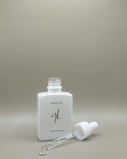 White bottle of naval oil with dropper on a beige background